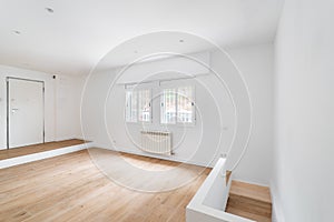 Empty white room with windows and hardwood floor after renovation. New apartment for rent or sale.