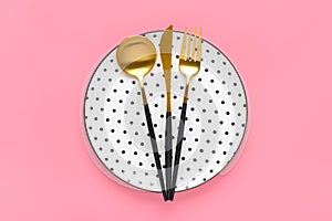 Empty white round plate with black peas, fork, knife, spoon on trendy pink background Top view Flat lay Dishes for breakfast,