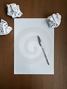 Empty white sheet, pen and crumpled paper on wooden office desk