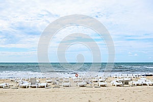 Empty white sun loungers on the sandy sea beach