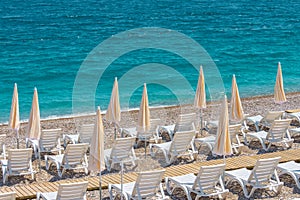 Empty white sun loungers white umbrellas at the sandy beach of Mediterranean Sea, vacation summer