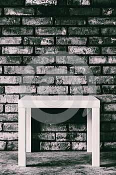 Empty white table against a brick wall, black and white photo.