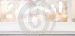 Empty white table top, counter, desk over blur perspective store with bokeh light background, White marble stone table, shelf and