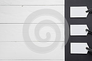 Empty white tags in a row on white and black wooden background. Top view. Mock up sample. Blank price tag on wooden planks. Design