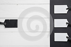 Empty white tags in a row on white and black wooden background. Top view. Mock up sample. Blank price tag on wooden planks. Design