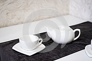 Empty white tea set, cup, saucer and teapot on the table. Porcelain dishes, selective focus