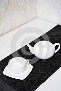 Empty white tea set, cup, saucer and teapot on the table. Porcelain dishes, selective focus