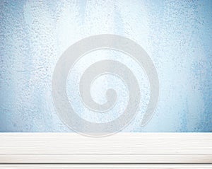 Empty white wooden table over blue cement wall.