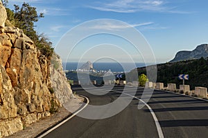 Empty winding mountain road and Calpe village at background