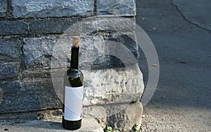 An empty wine bottle of a dark glass with a white label and a cow stopper.