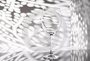 Empty wine glass with beautiful light pattern on background