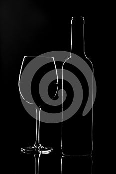 Empty wine glass and a bottle isolated on a dark background
