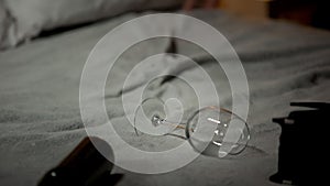 Empty wine glass and bottle lying on bed, alcohol abuse concept, alcoholism