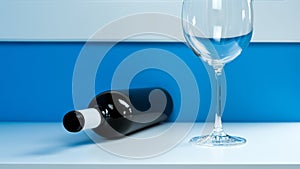 Empty wine glass on a white table next to an empty dark glass wine bottle