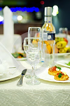 Empty wine glasses for alcoholic drinks and snacks stand on the served table