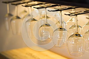 Empty wine glasses hanging on bar rack