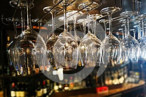 Empty wine glasses hanging on rack in bar