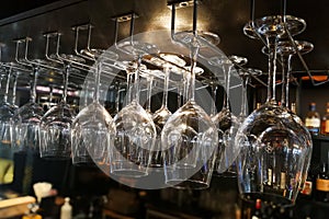 Empty wine glasses hanging on rack in bar