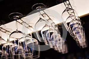 Empty wine glasses hanging upsidedown in bar interior.