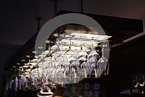 Empty wine glasses hanging upsidedown in bar interior.