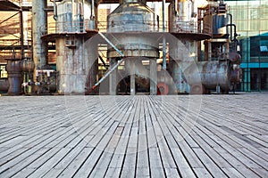 Empty wood floor road surface with old steel steelworks of pipelines