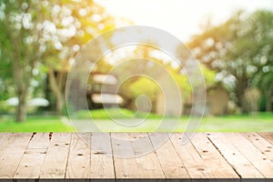 Empty wood table and defocused bokeh and blur background of garden trees in sunlight, display montage for product.