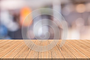 Empty wood table in front with blurred background of coffee shop