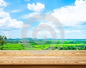 Empty wood table with green field and blue sky at background