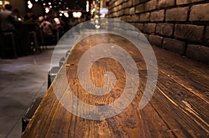 Empty wood table top of bar with blur of cafe restaurant in dark