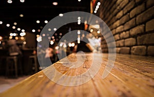 Empty wood table top of bar with blur of cafe restaurant in dark