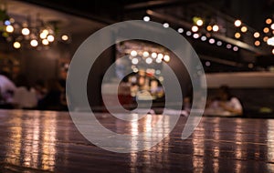 Empty wood table top on blur cafe restaurant in dark night with light background/selective focus