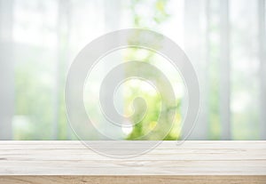 Empty of wood table top on blur of curtain with window view green from tree garden