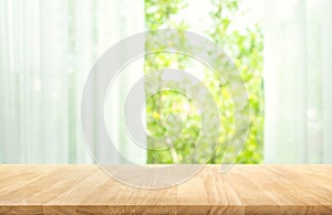 Empty of wood table top on blur of curtain with window view green from tree garden background