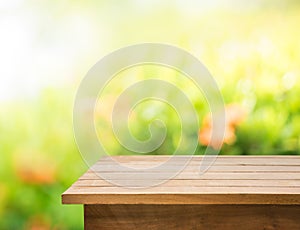 Empty of wood table top on blur of fresh green abstract from garden