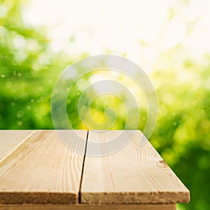 Empty of wood table top on blur of fresh green abstract from garden