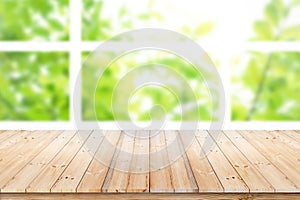 Empty wood table top on blur green leaf garden from window view in the morning.