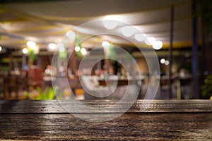 Empty wood table top and blur of night pub or restaurant background/selective focused.