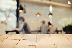 Empty wood table top with blur of people in coffee shop.