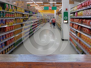 Empty wood table top on Blurred people shopping in selection of Snack on shelf in supermarket or department store, products on