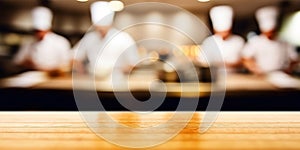 Empty Wood table top with Chef cooking in restaurant kitchen blurred defocused background