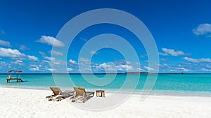 Empty wooden beach chairs on the tropical beach, vacation. Traveler dreams concept