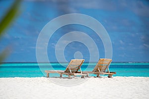 Empty wooden beach chairs on the tropical beach, vacation. Traveler dreams concept