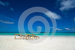 Empty wooden beach chairs on the tropical beach, vacation. Traveler dreams concept