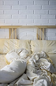 Empty wooden bed in the bedroom, with unmade light duvet