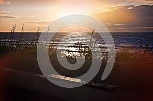 Empty wooden bench by the sea at sunset