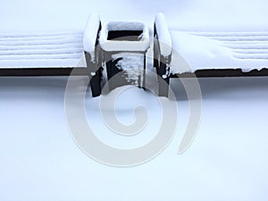 Empty wooden bench under snow after heavy snowfall