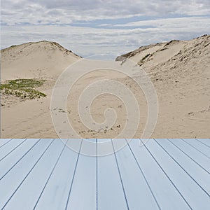 Empty wooden,blue table ready for your product display montage with dunes of sand in background, UK