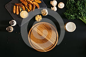 empty wooden board, glass of beer and baked potatoes with sauce and spices