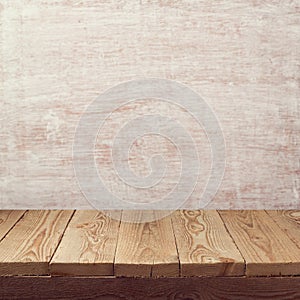 Empty wooden board table over painted white wall background for product montage