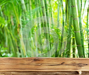 Empty wooden board or table top and blurred green bamboo culms. Place for your product display